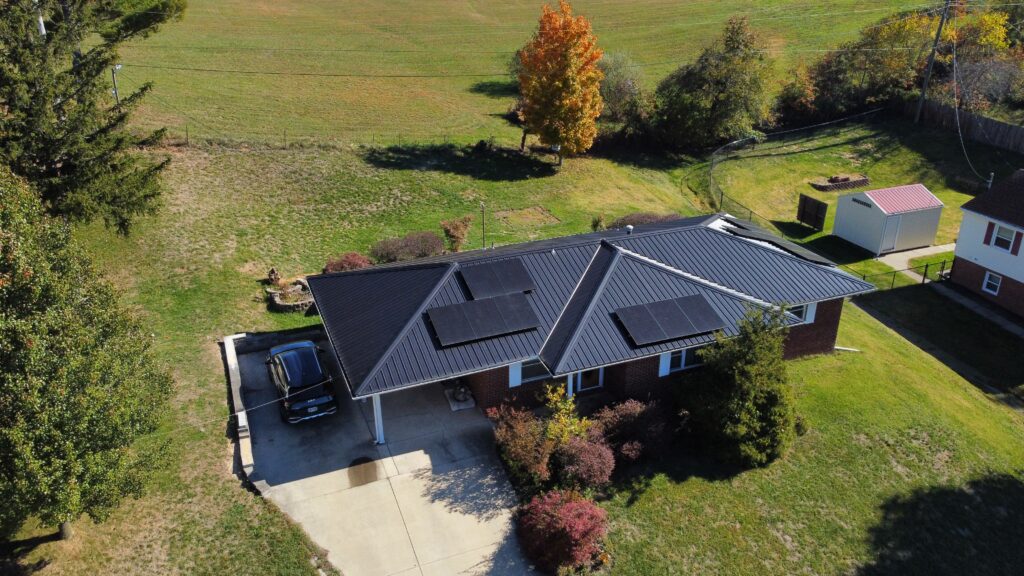 ranch style home with black roof and solar panels